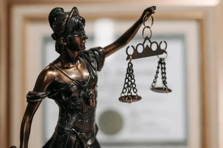 Close-up of a bronze Lady Justice statue holding scales in an office environment.